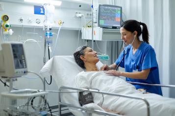 Nurse checking a patient in a hospital bed