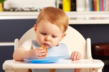 A baby sitting in a high chair eating food