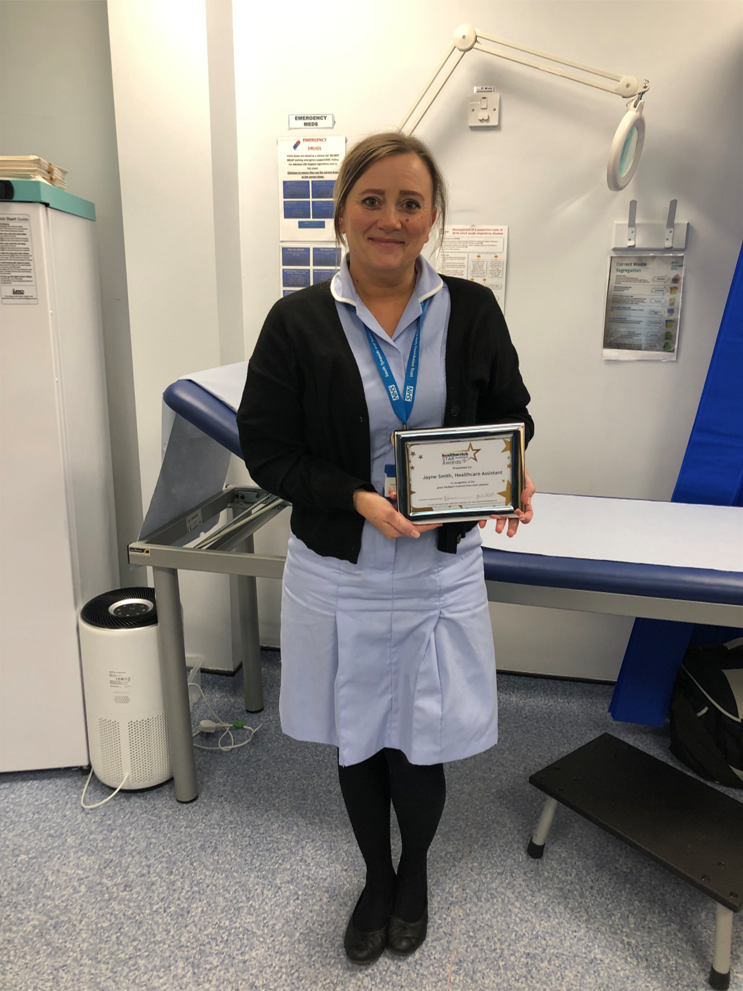 A lady standing looking at the camera holding a certificate