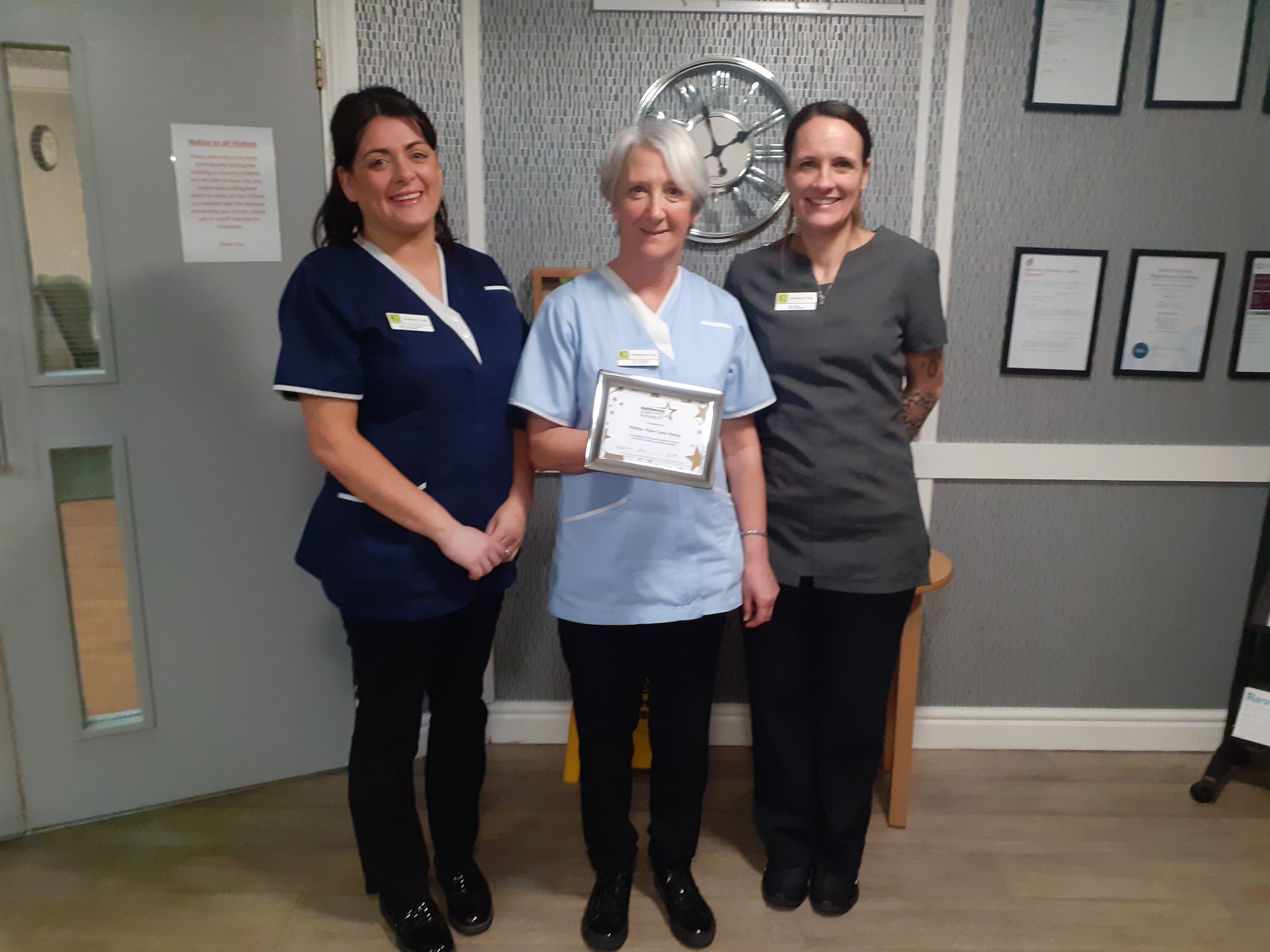 Three ladies holding a certificate and looking at the camera