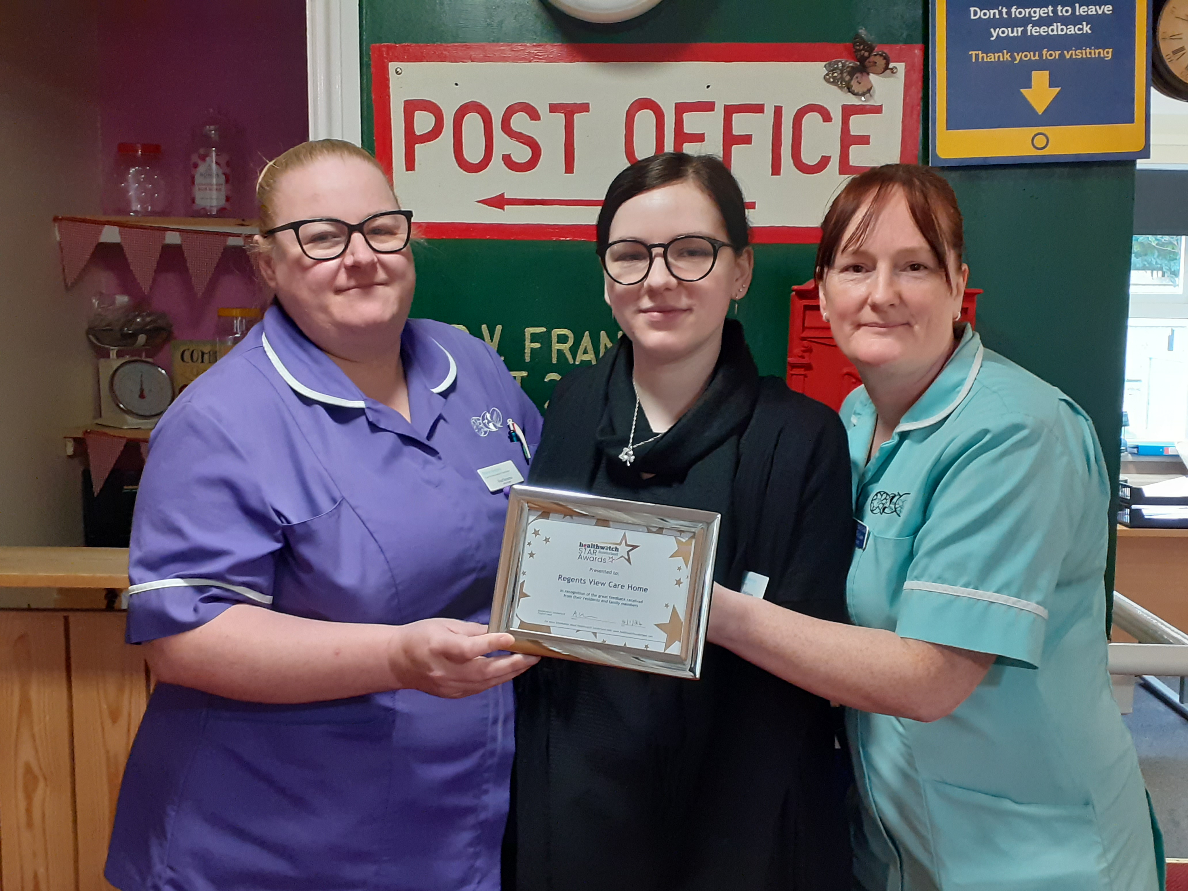 Three ladies holding a certificate and looking at the camera