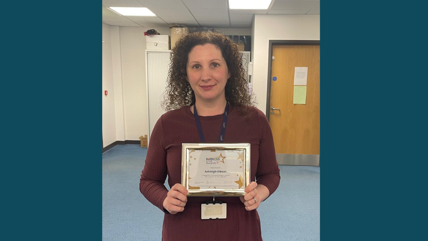 A lady standing looking at the camera holding a certificate