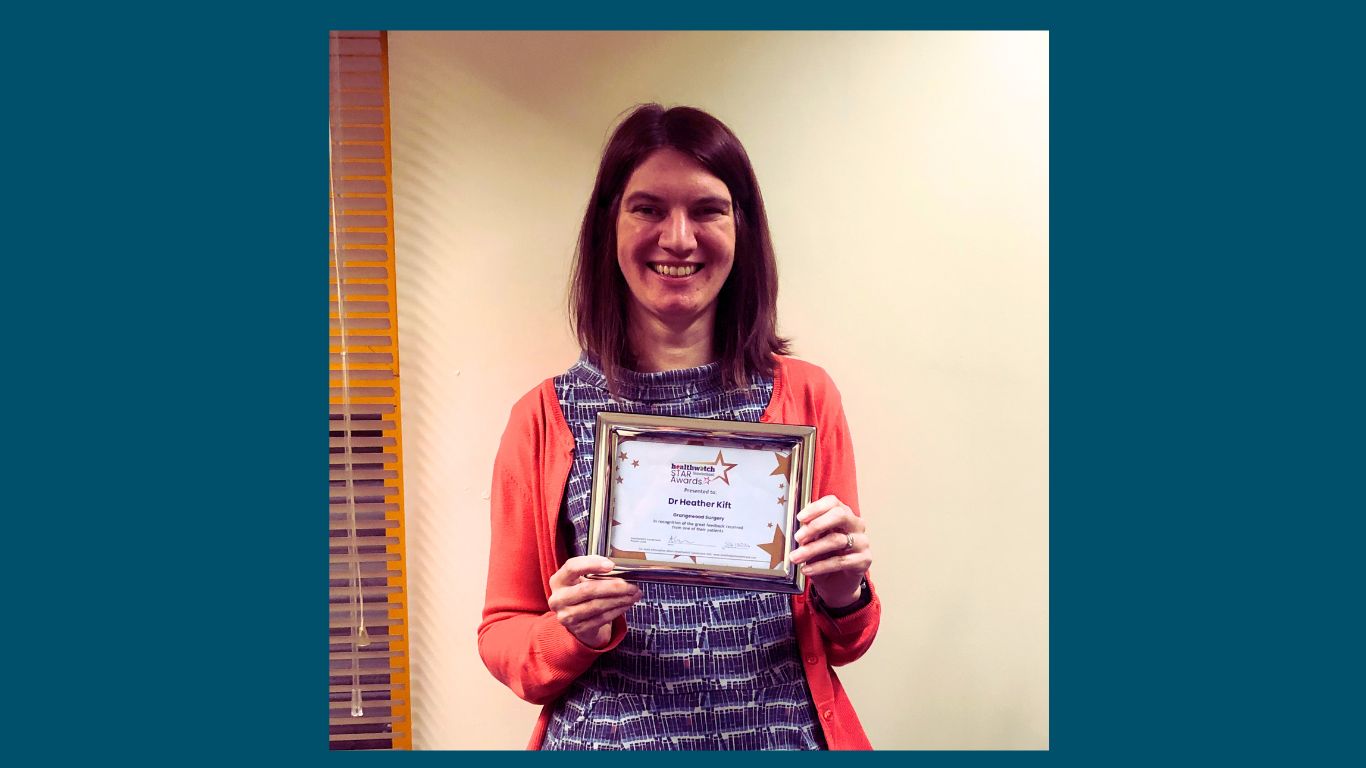 A lady standing looking at the camera holding a certificate