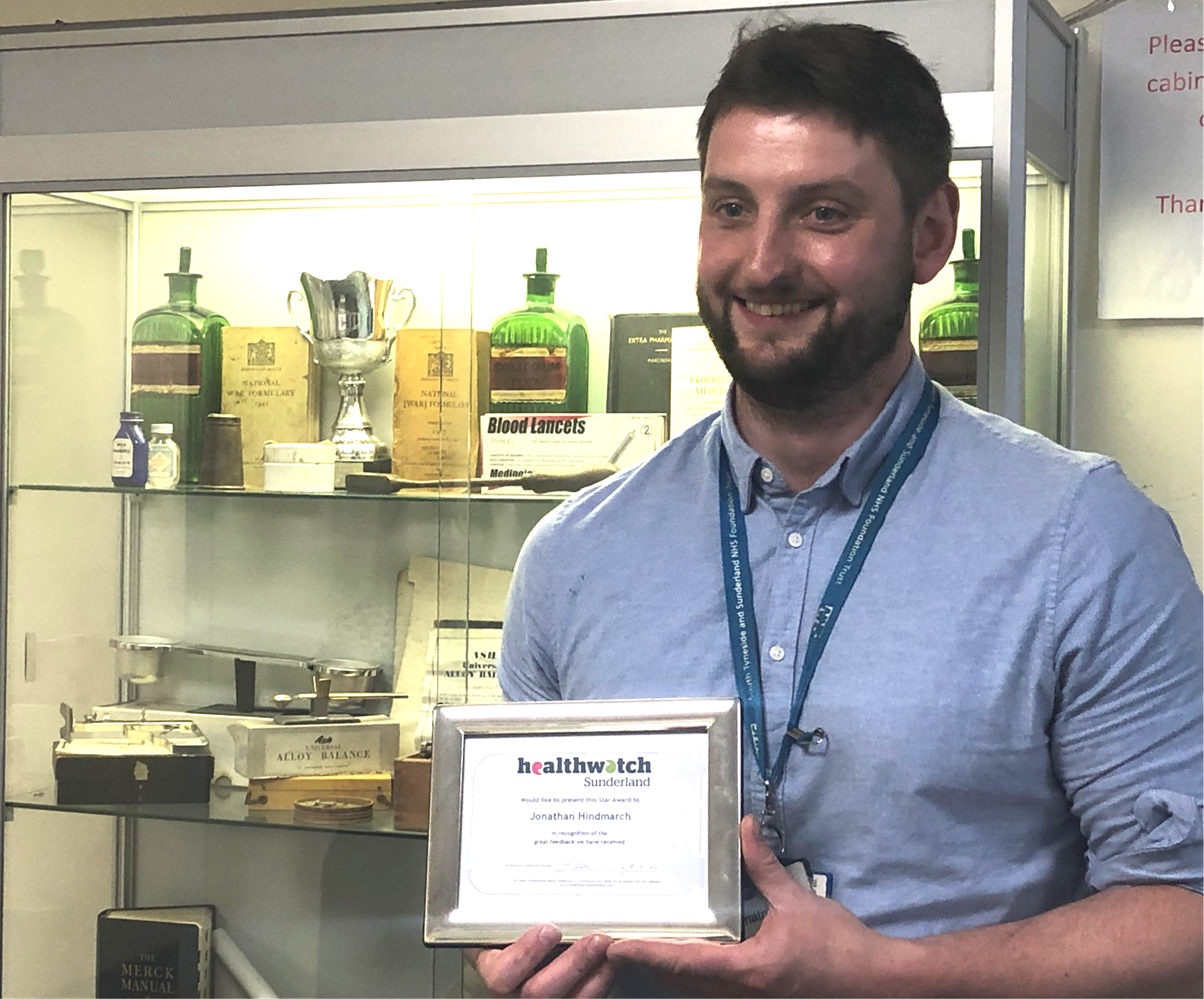 A man holding a Healthwatch Sunderland star award certificate smiling at the camera