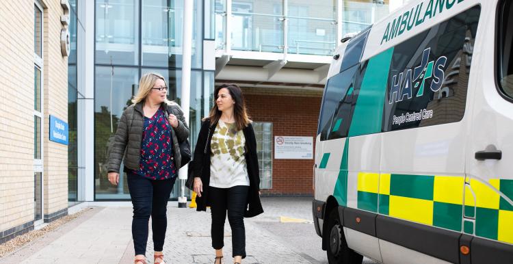 Two women outside a hospital near an ambulance Two women outside a hospital near an ambulance