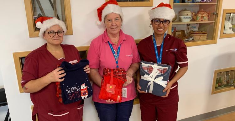 Three ladies holding pyjamas looking at the camera