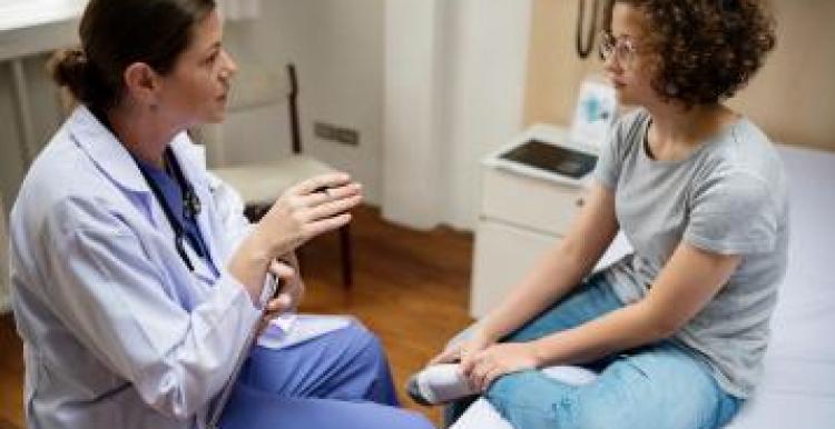 A young woman with a doctor in an exam room