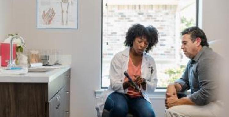 Mid adult female doctor points out something on the digital tablet to a mature adult