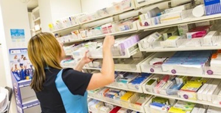 A lady stacking shelves in a pharmacy