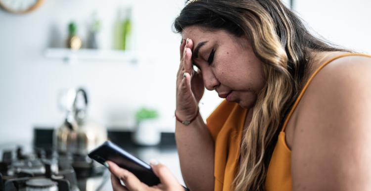 Worried mid adult woman of colour using a mobile phone in the living room at home