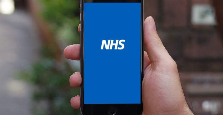 Image of a person holding a mobile phone with the NHS logo on