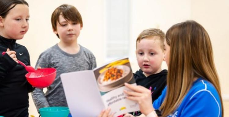 A woman showing some children recipes in a book 
