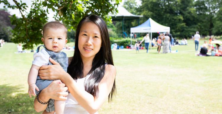 Mother holding baby standing in a park 