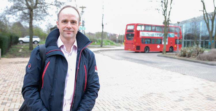Man stood outside near a roundabout and in front of a bus Man stood outside near a roundabout and in front of a bus