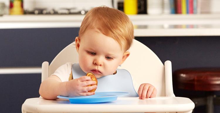 A baby sitting in a high chair eating food