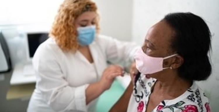 Woman injecting a woman with the COVID-19 vaccine Woman injecting a woman with the COVID-19 vaccine