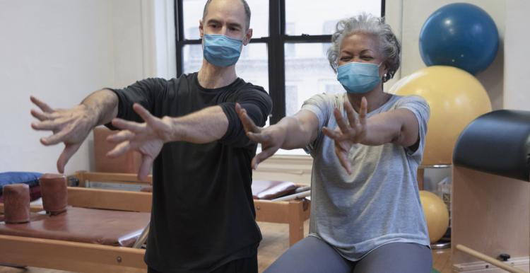 A man and a woman sitting on exercise balls. Their arms are stretched out in front of them. A man and a woman sitting on exercise balls. Their arms are stretched out in front of them.