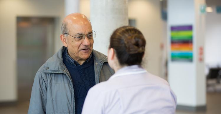Man speaking to someone working in a health centre Man speaking to someone working in a health centre