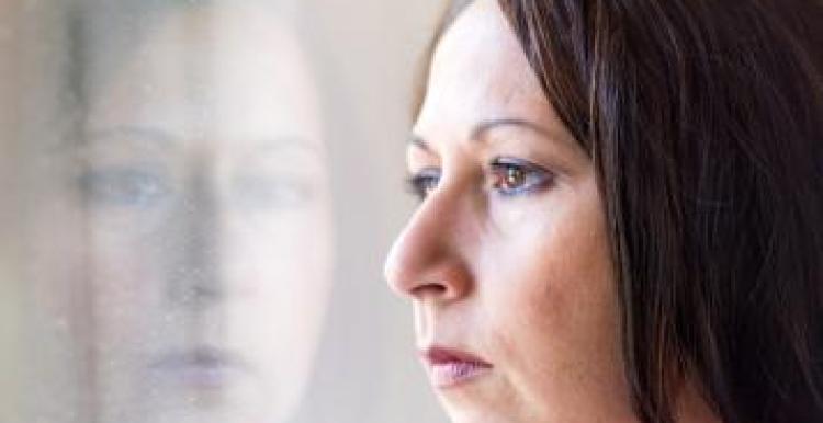 A woman looking out of the window with a serious facial expression