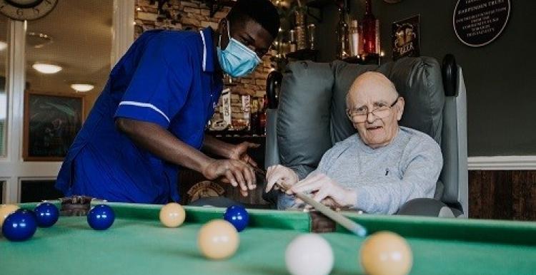A nurse with a patient playing a table game