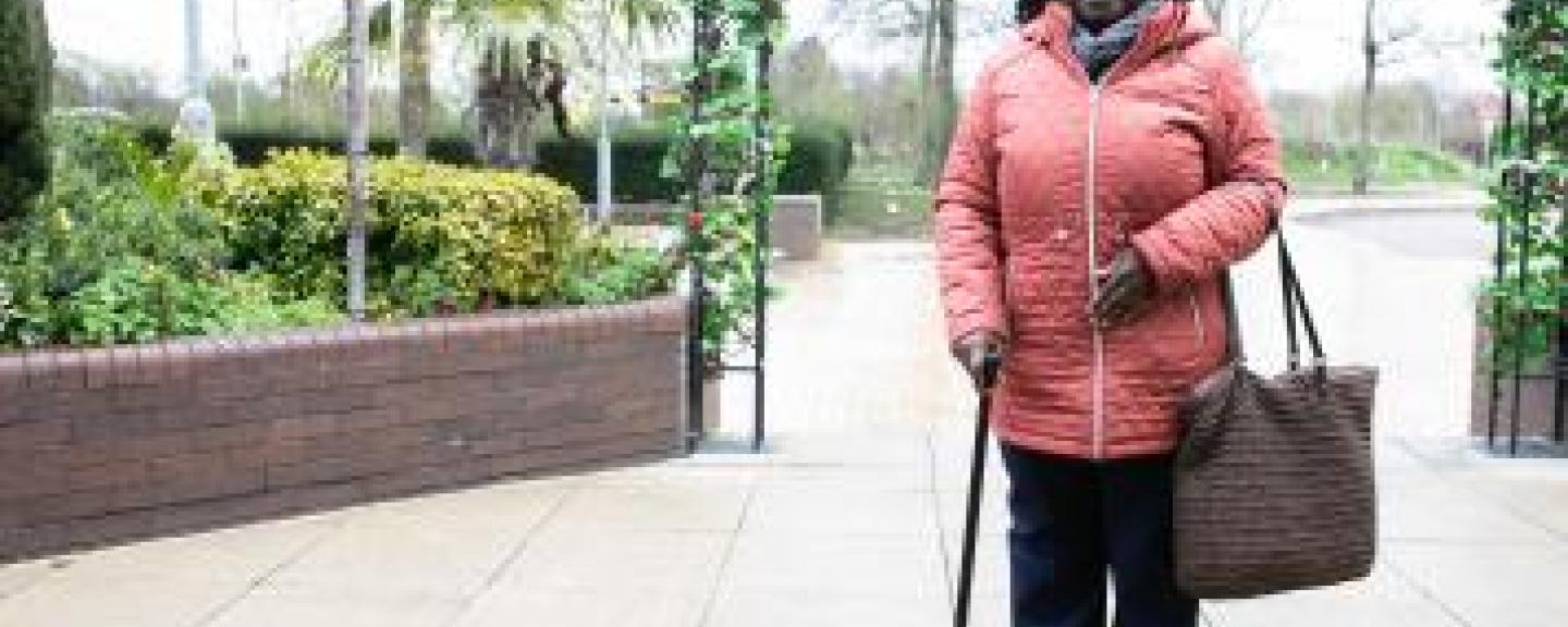 Woman with a walking stick looking at the camera