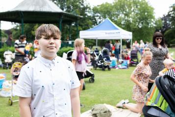 A young boy at a community event, standing in front of a crowd