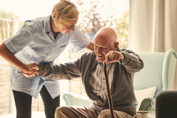 A Nurse helping a man out of a chair