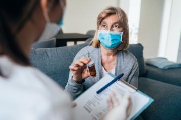 A lady wearing a mask talking to another person