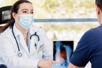 A nurse wearing a face mask talking to a man