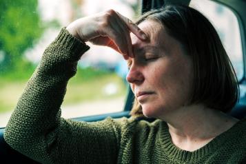 A woman sitting with her hand on her head