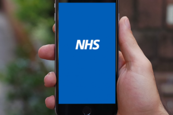 Image of a person holding a mobile phone with the NHS logo on