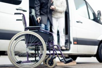 A person being helped out of a car to their wheelchair