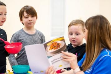 A woman showing some children recipes in a book 