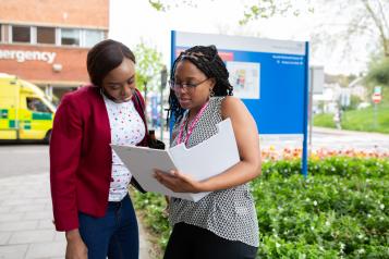 Two people looking at a folder outside a hospital