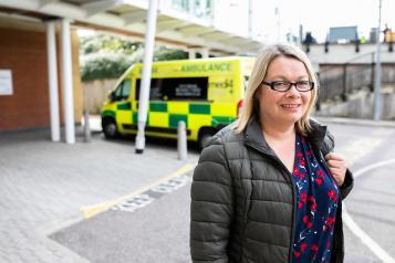 A woman standing in front of a ambulance, outside hospital