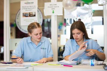 Two female students sitting at a desk of paperwork