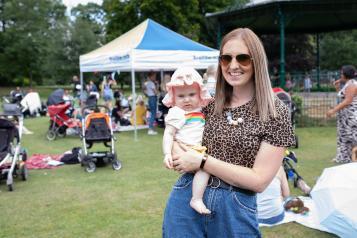 Mother holding her baby looking at the camera at a Healthwatch event