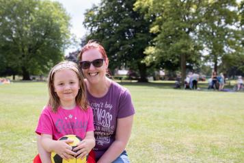 Mother with her arms round her daughter in the park