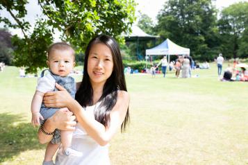 Mother holding baby standing in a park 