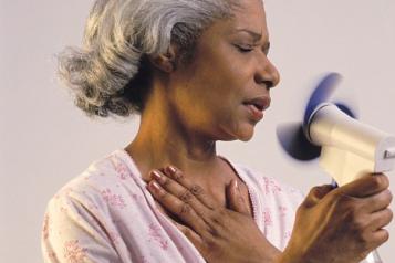 A woman holding a fan to cool her face