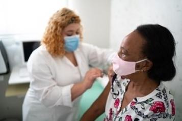 Woman injecting a woman with the COVID-19 vaccine