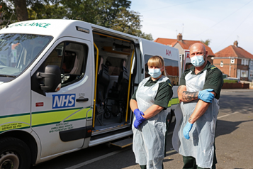 Two people standing in front of a NEAS Transport Vehicle