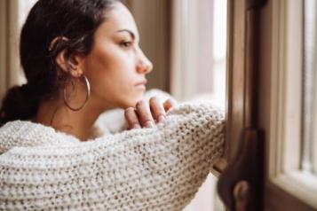 Woman looking out of window, looking pensive