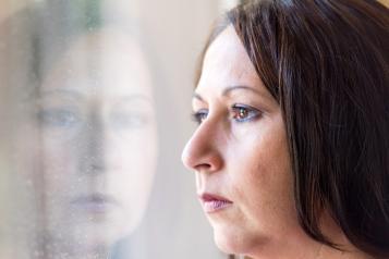 A woman looking out of the window with a serious facial expression