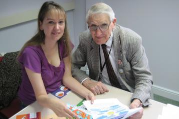 woman and elderly gentleman sat at a desk over some paperwork