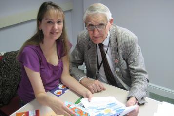 woman and elderly gentleman sat at a desk over some paperwork