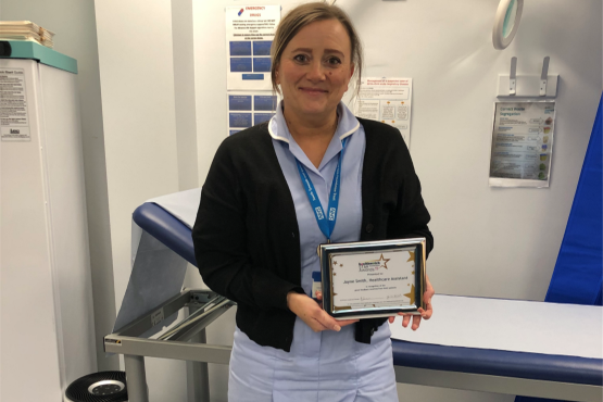 A lady standing looking at the camera holding a certificate