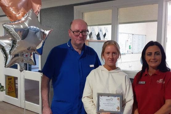 Three people holding a certificate and looking at the camera