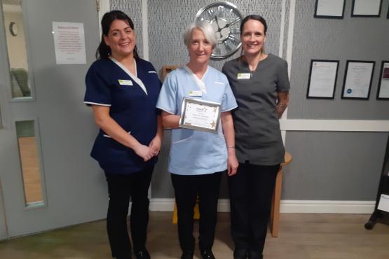 Three ladies holding a certificate and looking at the camera