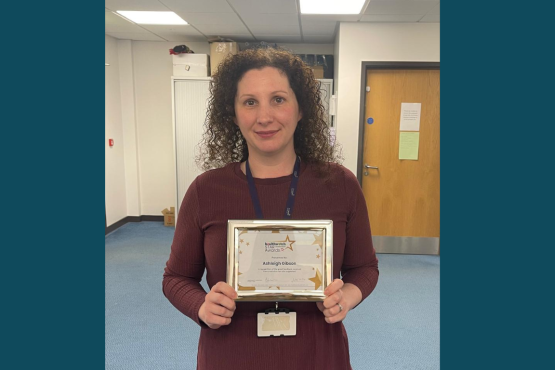 A lady standing looking at the camera holding a certificate